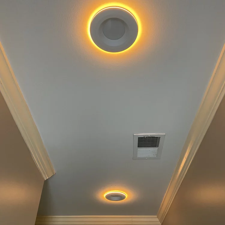 Ceiling view of a modern residential interior featuring two circular LED lights with a warm glow, set against a white ceiling.