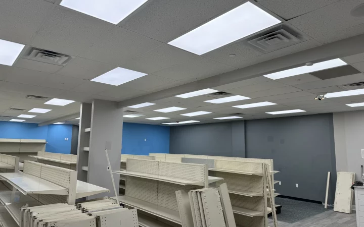 An empty commercial space prepared for fit-out, with shelving units in place and a newly installed ceiling with LED lights.