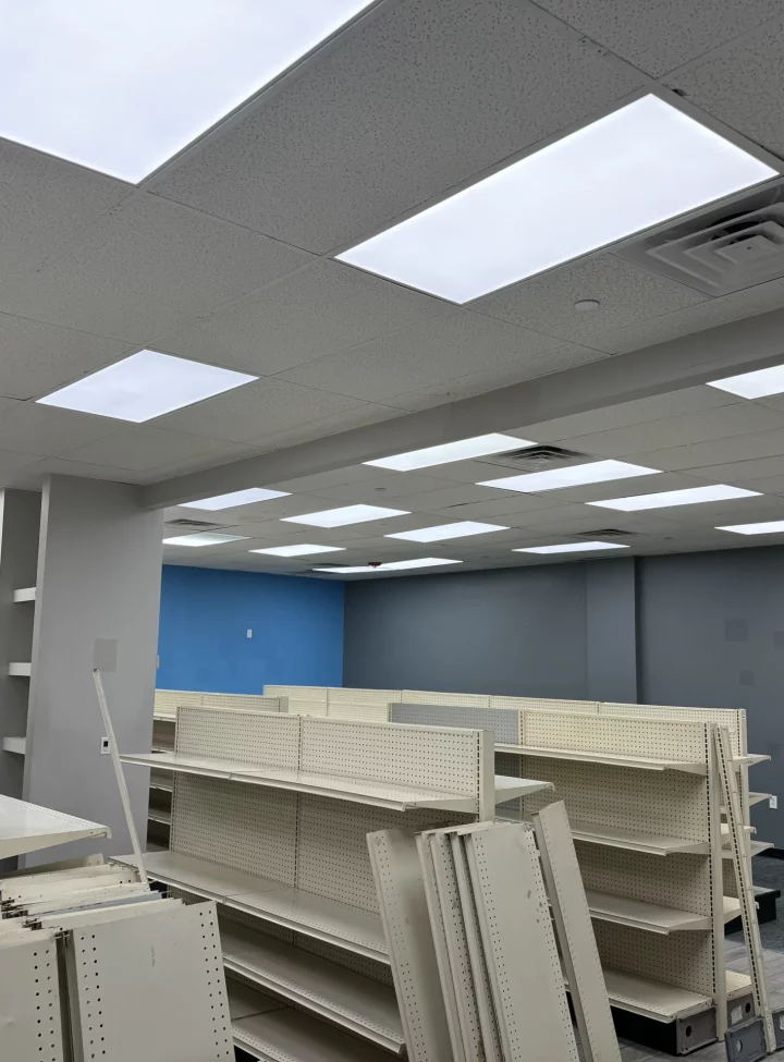 An empty commercial space prepared for fit-out, with shelving units in place and a newly installed ceiling with LED lights.