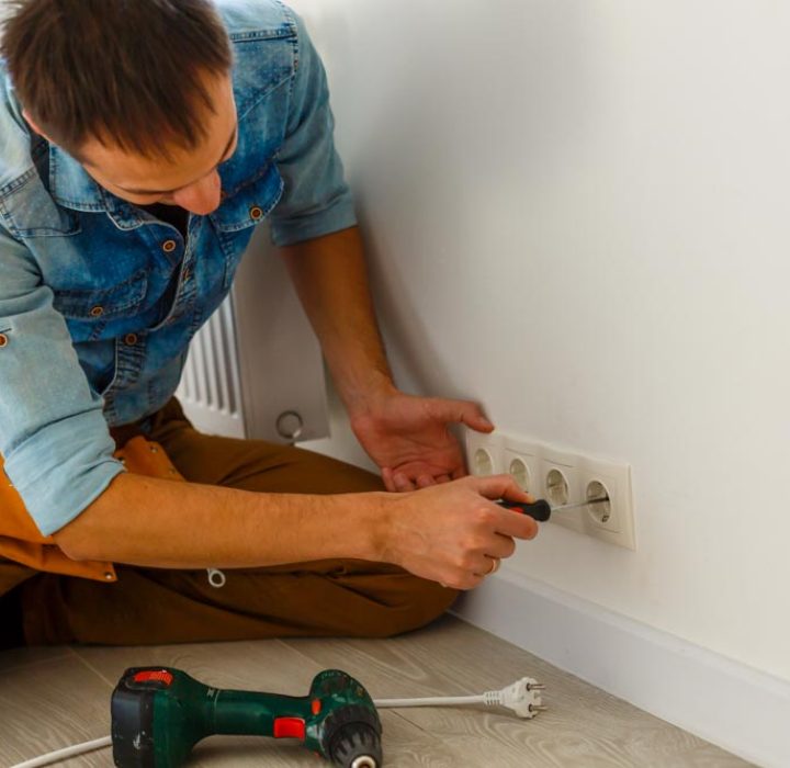 Electrician checking outlet voltage with digital multimeter