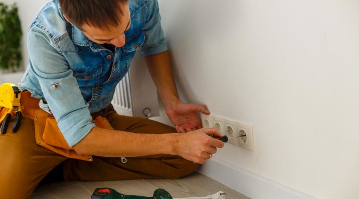Electrician checking outlet voltage with digital multimeter